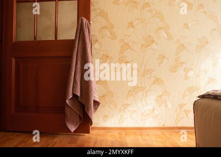 Badehandtuch hing am Türgriff im Schlafzimmer des Hauses und das Licht von Stockfoto