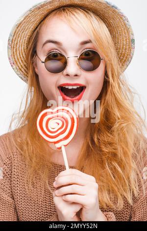 Ich habe eine junge Blondine mit Sonnenbrille und Lutscher überrascht Stockfoto