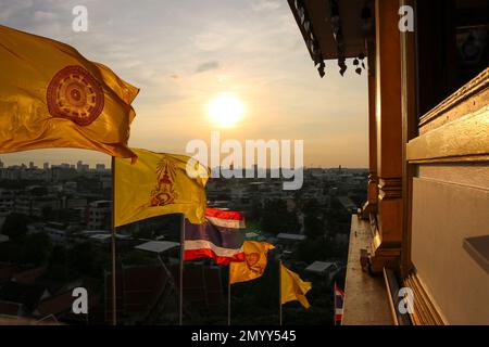 Dharmachakra-Flaggen und nationale thailändische Flagge bei Sonnenuntergang in Bangkok, Goldener Mount-Tempel (Wat Saket), Thailand. Stockfoto