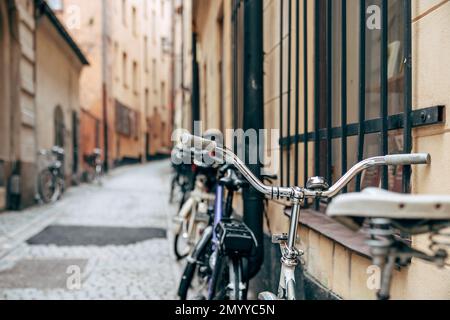 Ein klassisches Fahrrad, das sich an die Wand einer Straße mit verwischtem Hintergrund lehnt Stockfoto