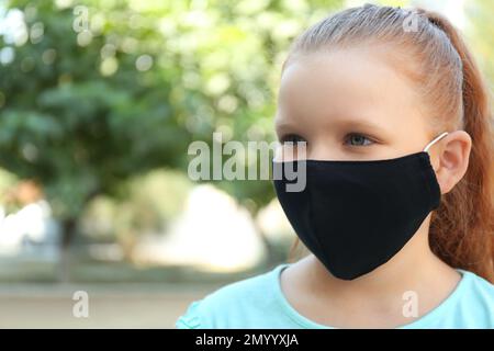 Ein junges Mädchen mit Gesichtsschutzmaske im Freien Stockfoto