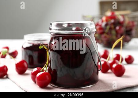 Eingelegte Kirschgläser und frisches Obst auf dem Tisch Stockfoto