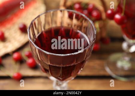 Köstlicher Kirschwein im Glas auf einem Holztisch, Nahaufnahme Stockfoto