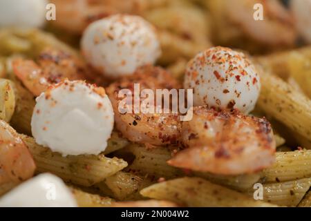 Penne mit Garnelen und Mozzarella und Pesto in blauer Schale, flacher Fokus Stockfoto