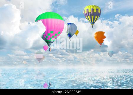 Fantastische Träume. Heißluftballons am Himmel mit flauschigen Wolken über dem Meer Stockfoto