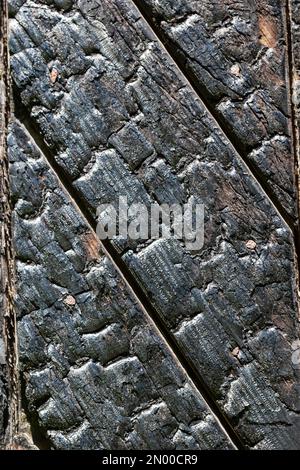 Schwarze Holzbrettstruktur, Nahaufnahme. BBQ-Hintergrund. Gebrannte Holztafel. Verbrannte, zerkratzte Hartholzoberfläche. Hintergrund: Raucherholzplanke. Bu Stockfoto