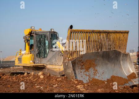 Mülldeponie. Arbeiter mit Lastwagen und Planierraupen arbeiten auf Mülldeponien. Stockfoto