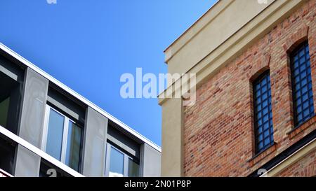 Moderne Ziegel- und Glasfassade des Bürogebäudes. Eine kontrastierende Kombination aus Himmel und Ziegeltextur auf einem Gebäude. Die architektonische Fassade eines Roten Stockfoto