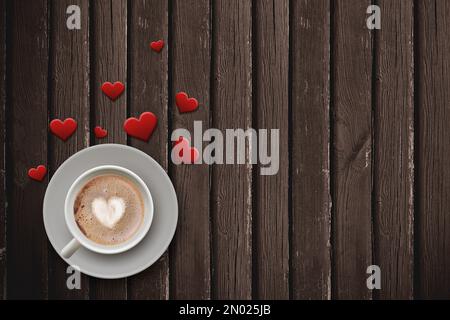 Valentinswoche, besondere Illustrationsidee. Kaffeebecher mit Herzmotiv und verstreute Herzen auf Holzboden. Leerer Platz. Stockfoto