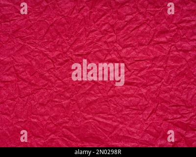 Rote zerknitterte Papierstruktur. Leeres dunkles Seitenmuster für Weihnachtsfestkarte im Winter, Neujahrsdesigns Dekoration, Hintergrundkonzepte, Text Stockfoto