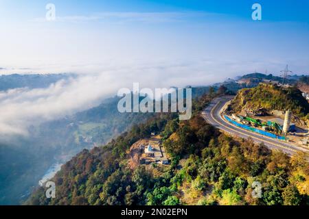 Die Drohne aus der Luft wurde vom Mountain Hill Road Highway aufgenommen, wobei Autos auf dem Highway in ein Tal mit Nebel-Wolken fahren, die sich bis in die Ferne erstrecken Stockfoto