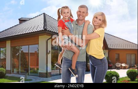 Glückliche Familie steht an einem sonnigen Tag vor ihrem Haus Stockfoto