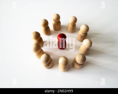 Rote Holzfigur, umgeben von einer anderen Puppenfigur. Belästigungskonzept. Stockfoto