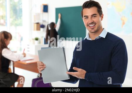 Junger Schullehrer im Klassenzimmer mit Schülern Stockfoto