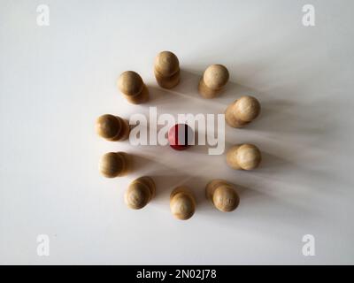 Ansicht der roten Holzfigur von oben, umgeben von einer anderen Puppenfigur. Belästigungskonzept. Stockfoto