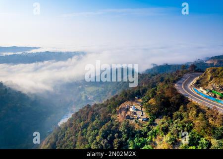 Die Drohne aus der Luft wurde vom Mountain Hill Road Highway aufgenommen, wobei Autos auf dem Highway in ein Tal mit Nebel-Wolken fahren, die sich bis in die Ferne erstrecken Stockfoto