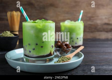 Leckerer Milchblasentee mit grüner Matcha auf schwarzem Holztisch, Nahaufnahme Stockfoto