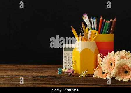 Set aus Schreibwaren und Blumen auf einem Holztisch in der Nähe der Tafel, Platz für Text. Lehrertag Stockfoto