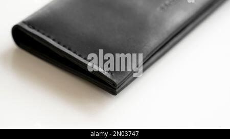 Geldbörse aus echtem schwarzem Leder mit Schlitzen für Karten und großer Reißverschlusstasche auf weißem Hintergrund. Accessoires für Herren. Stockfoto