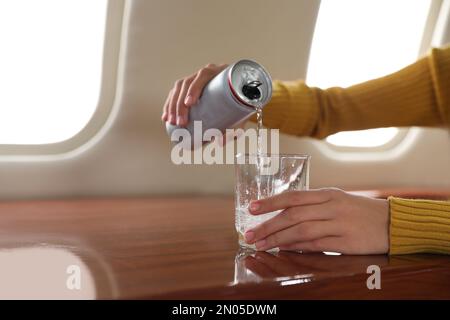 Frau, die Wasser ins Flugzeug gießt, Nahaufnahme. Bequemer Flug Stockfoto