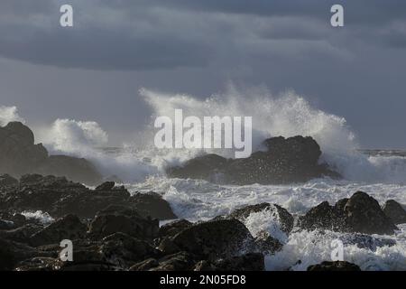 Meereswelle spritzt gegen den bewölkten Himmel. Nördliche portugiesische felsige Küste. Stockfoto