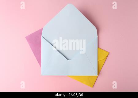 Farbige Papierumschläge auf pinkfarbenem Hintergrund, Draufsicht Stockfoto
