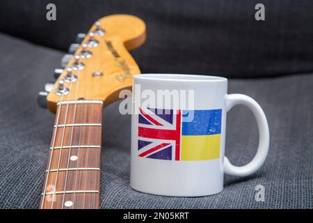 Unterstützung für die Ukraine. Musiker unterstützen ukrainische Hilfe. Gitarre und Kaffeetasse. Ukraine Relief, DEZ, Rotes Kreuz Fonds.Ukraine Flagge, Union Jack Stockfoto