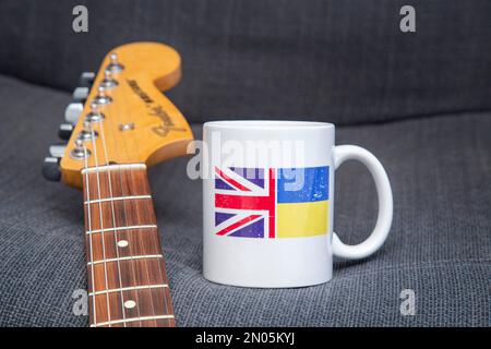 Unterstützung für die Ukraine. Musiker unterstützen ukrainische Hilfe. Gitarre und Kaffeetasse. Ukraine Relief, DEZ, Rotes Kreuz Fonds.Ukraine Flagge, Union Jack Stockfoto