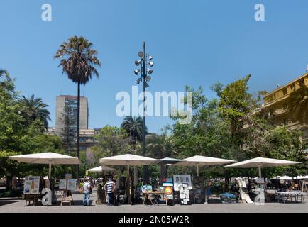 Einige der Verkaufsstände mit Kunstwerken oder Porträt- oder Karikaturdiensten im historischen plaza de Armas im Stadtzentrum von Santiago de Stockfoto