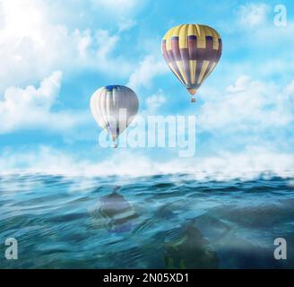 Traumwelt. Heißluftballons am Himmel mit Wolken über dem nebligen Meer Stockfoto