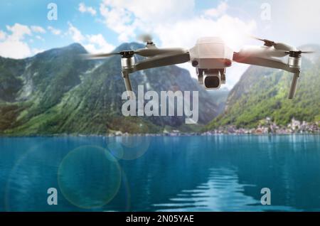 Moderne Drohne, die über den See in der Nähe der malerischen Berge fliegt. Luftaufnahme Stockfoto