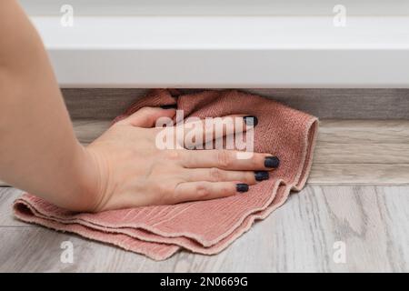 Eine Frau wäscht den Boden an einem schwer erreichbaren Ort. Frau, die den Boden im Zimmer nass reinigt. Hausreinigung. Stockfoto