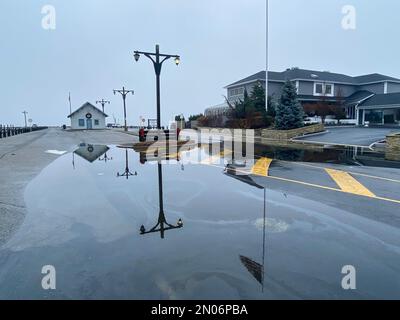 Das Wasser der Bucht fließt weiter zu den Docks und Straßen in Babylon Village und bildet große und gefährliche Pfützen, durch die Autos fahren können. Stockfoto