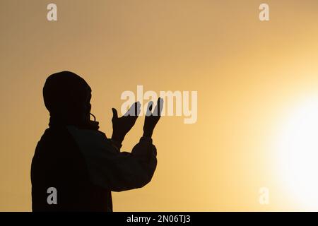 Mann betet bei Sonnenuntergang Berge erhöhte Hände Reisen Lifestyle spirituelle Entspannung emotionales Konzept, Freiheit und Reiseabenteuer. Stockfoto