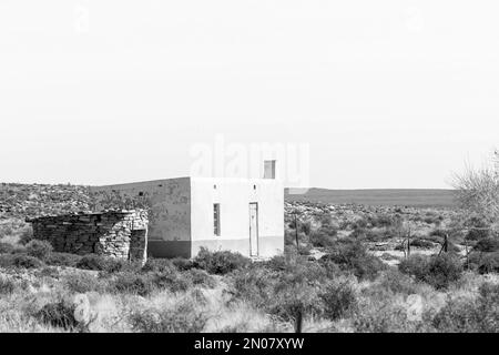 Fraserburg, Südafrika - 3. September 2022: Ein Bauernhaus neben der Straße R356 in der Nähe von Fraserburg im nördlichen Kap Karoo. Schwarzweiß Stockfoto