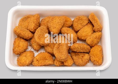 Vorgekochte Chicken Nuggets in einer Plastikschale für Supermärkte, isoliert auf grau mit Abschneideweg Stockfoto