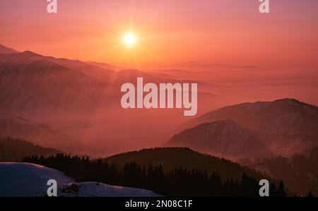 Magische Atmosphäre eines Sonnenuntergangs am Abend im Hochland; Bergketten und Täler umgeben von sanftem Nebel bei Sonnenuntergang Stockfoto