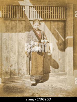 Ein Foto einer Japanerin, die Tee serviert. Veröffentlicht in „Views & Costumes of Japan“ von Stillfried und Andersen (Yokohama, 1877). Stockfoto