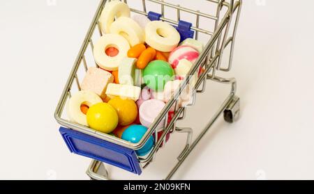 Viele bunte, verschiedene Süßigkeiten in einem kleinen Einkaufswagen. Stockfoto