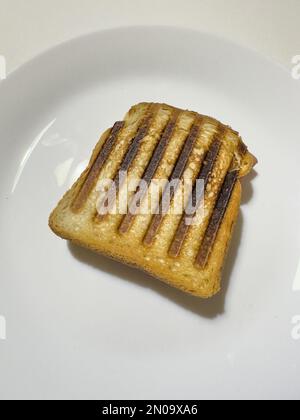 Italienischer Toast mit frischem Schinken und Käse, hausgemacht auf weißem Teller, gegrilltes Käse-Sandwich Stockfoto