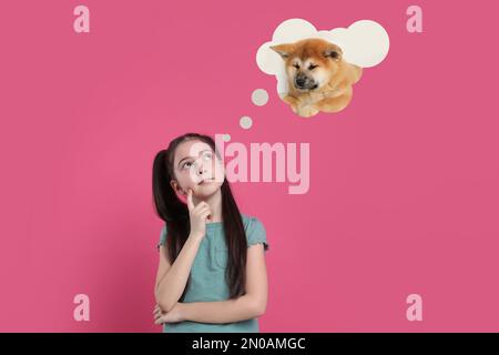 Ein kleines Mädchen träumt von einem süßen Welpen mit rosa Hintergrund Stockfoto
