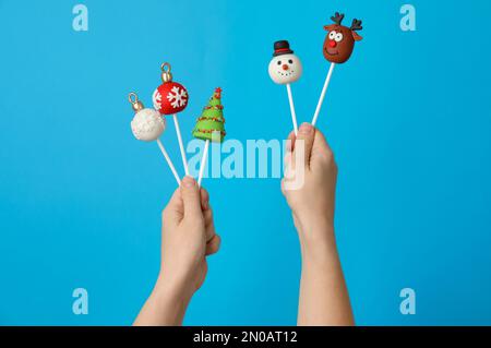 Eine Frau mit köstlichem Weihnachtskuchen vor hellblauem Hintergrund, Nahaufnahme Stockfoto