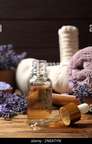 Zusammensetzung mit Lavendelblumen und ätherischem Öl auf Holztisch Stockfoto