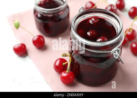 Eingelegte Kirschgläser und frisches Obst auf dem Tisch, Nahaufnahme Stockfoto