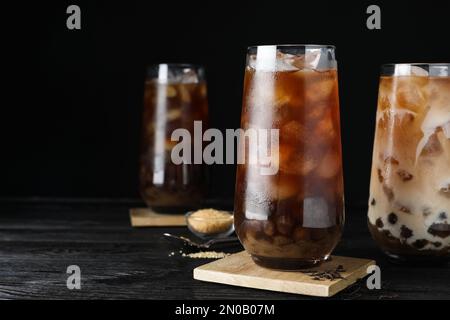 Leckerer brauner Milchblasentee auf schwarzem Holztisch. Platz für Text Stockfoto