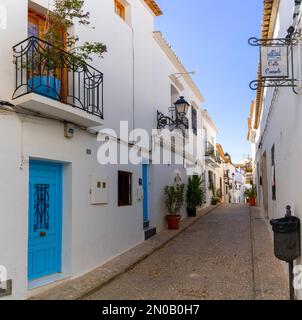 Altea, Spanien - 3. Februar 2023: Enge Straße mit weiß getünchten Hausfassaden im historischen Stadtzentrum von Altea an der spanischen Küste Stockfoto
