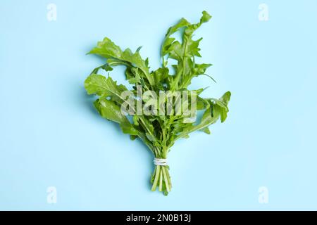 Frischer Rucola auf hellblauem Hintergrund, Draufsicht Stockfoto