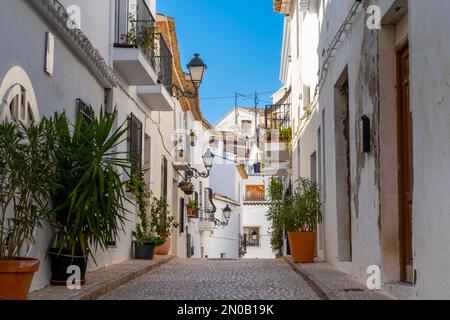 Altea, Spanien - 3. Februar 2023: Enge Straße mit weiß getünchten Hausfassaden im historischen Stadtzentrum von Altea an der spanischen Küste Stockfoto