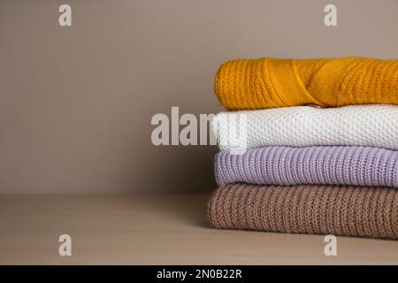 Stapel gefalteter Strickpullover auf Holztisch. Platz für Text Stockfoto