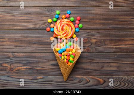 Waffelkonus voller traditioneller Süßigkeiten, die auf farbigen Hintergrund fallen, mit Platz für Kopien. Frohes Weihnachtsangebot. Stockfoto